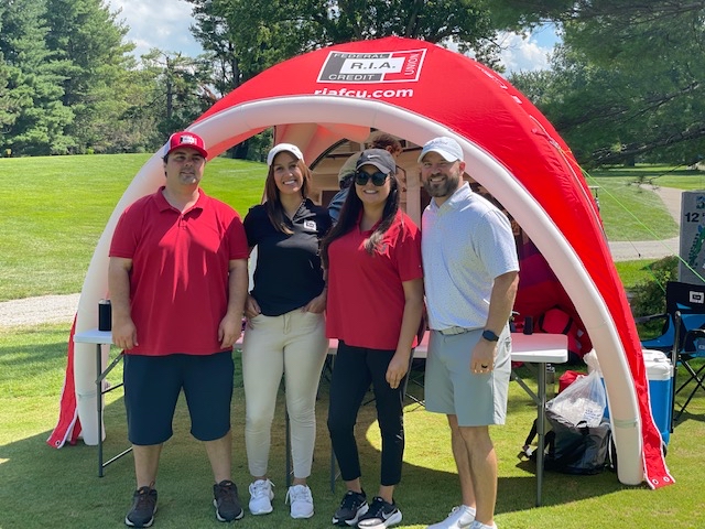 Mortgage team stands in front of R.I.A. tent at golf outing
