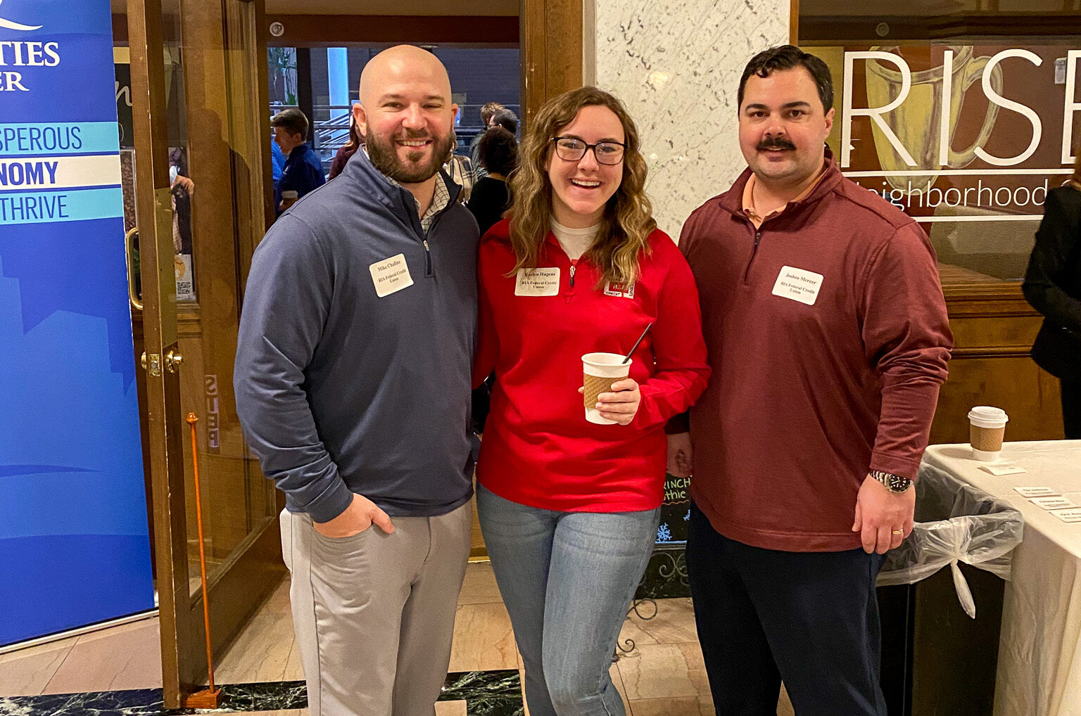 Three employees stand together at QC Chamber Coffee Meet Up