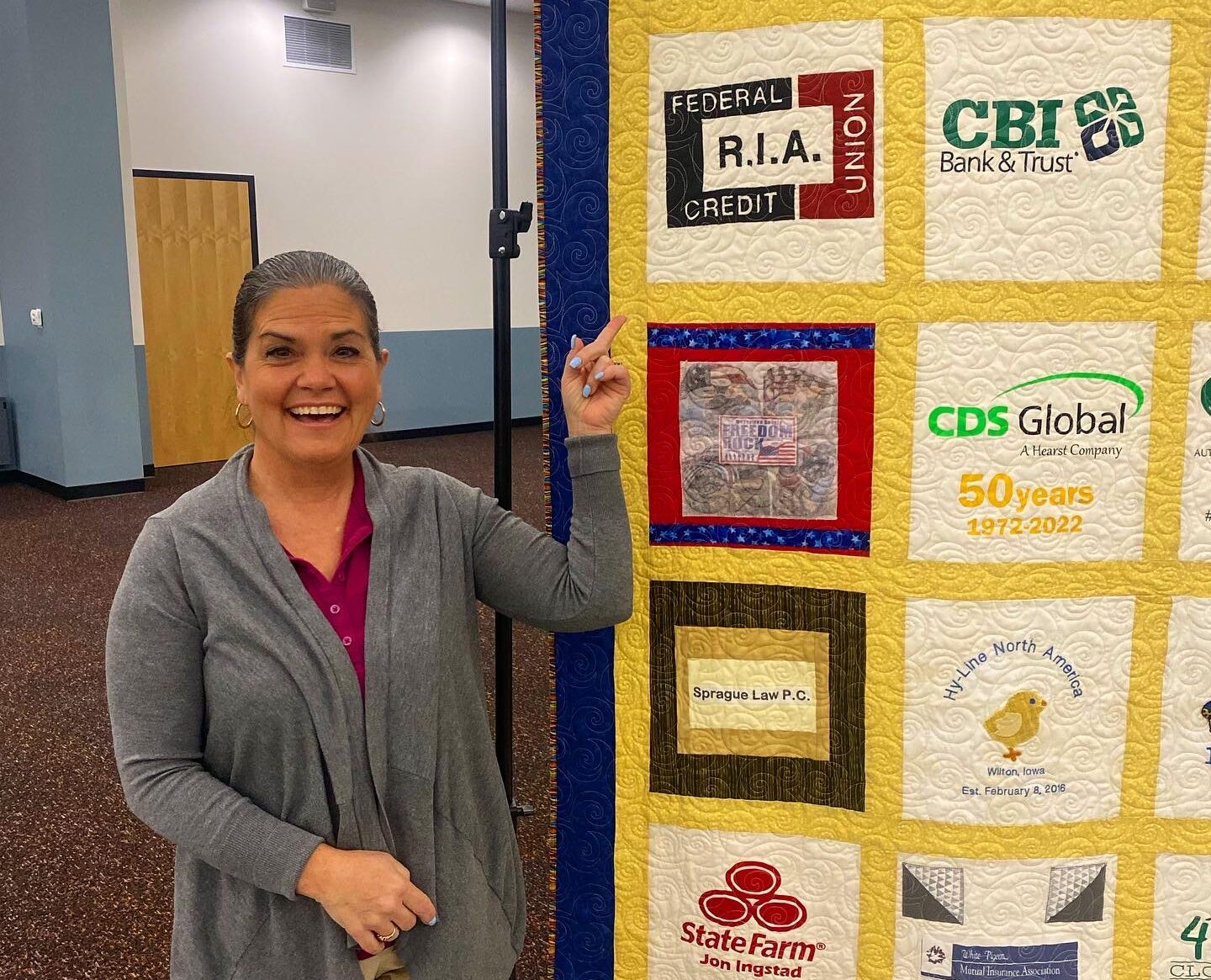 Susan standing next to R.I.A. sqaure on Wilton Library quilt