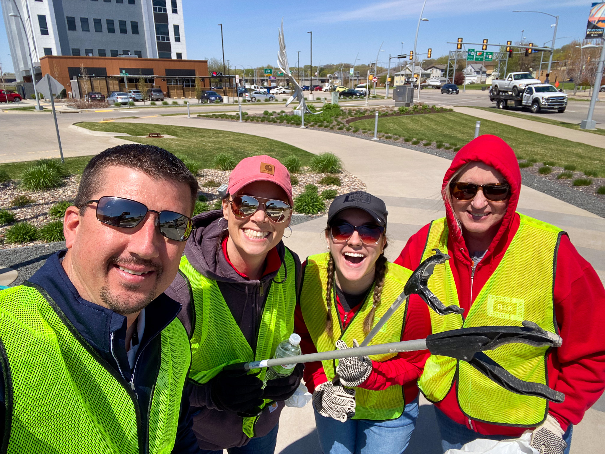 Group of employees wearing safety vests and cleaning up garbage